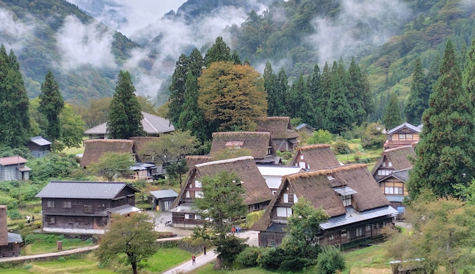 Traditional Japanese mountain village with thatched-roof houses nestled in a misty valley